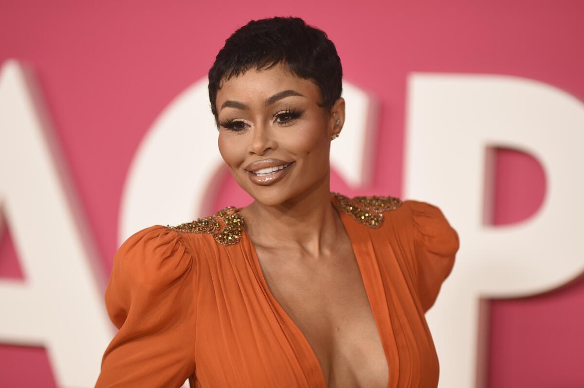 Blac Chyna smiles as she arrives at an event in fancy orange dress with short black hair