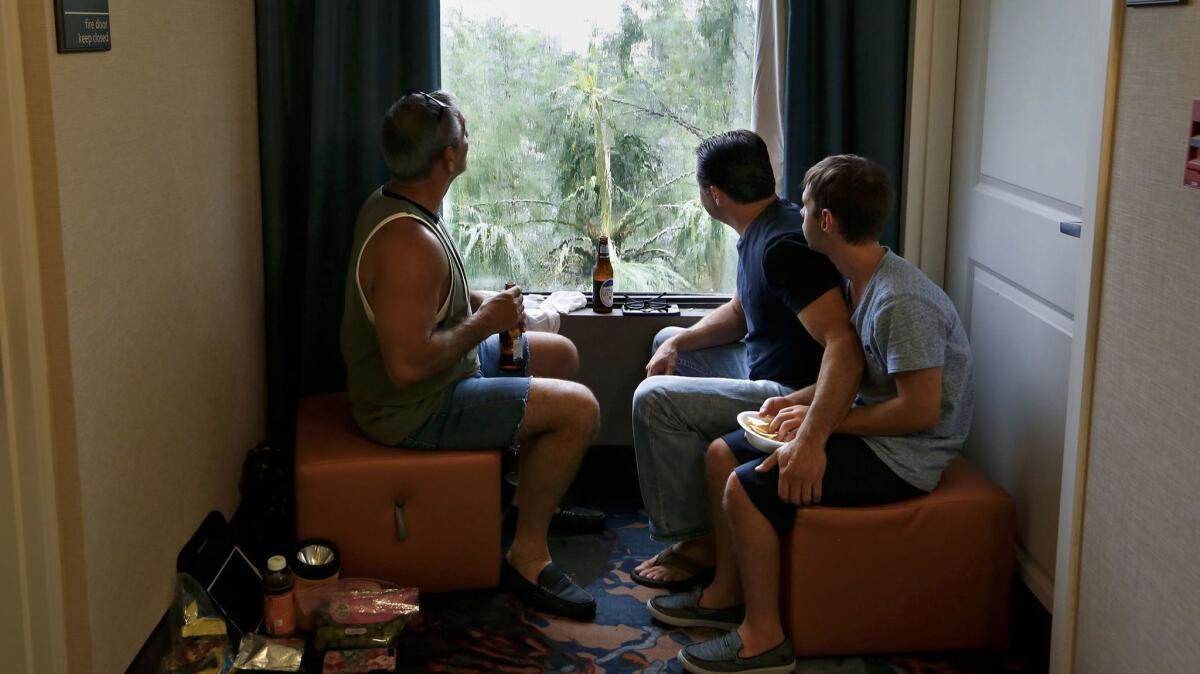 Jimmy Alfano, right, of Fort Myers, Fla., holds onto Alec Hoskins, who is autistic, while watching the gusty storm with Frank Pair, left, and drinking beers.