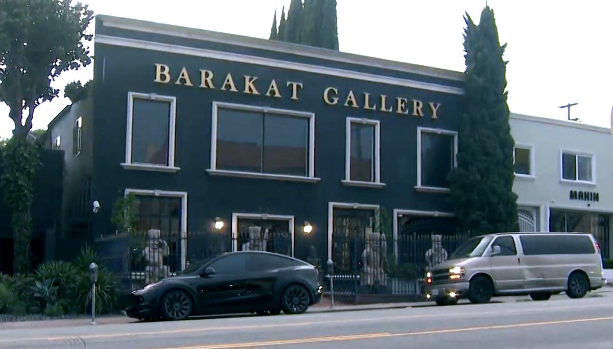 An exterior view of a dark blue two-story building with large glass windows and the words Barakat Gallery