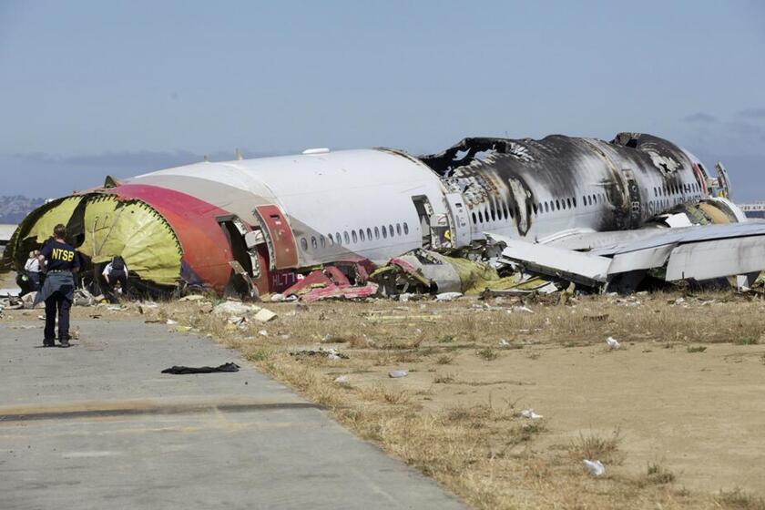 An National Transportation Safety Board investigator looks at the fuselage of the crashed Asiana Flight 214 during the first site assessment in San Francisco.