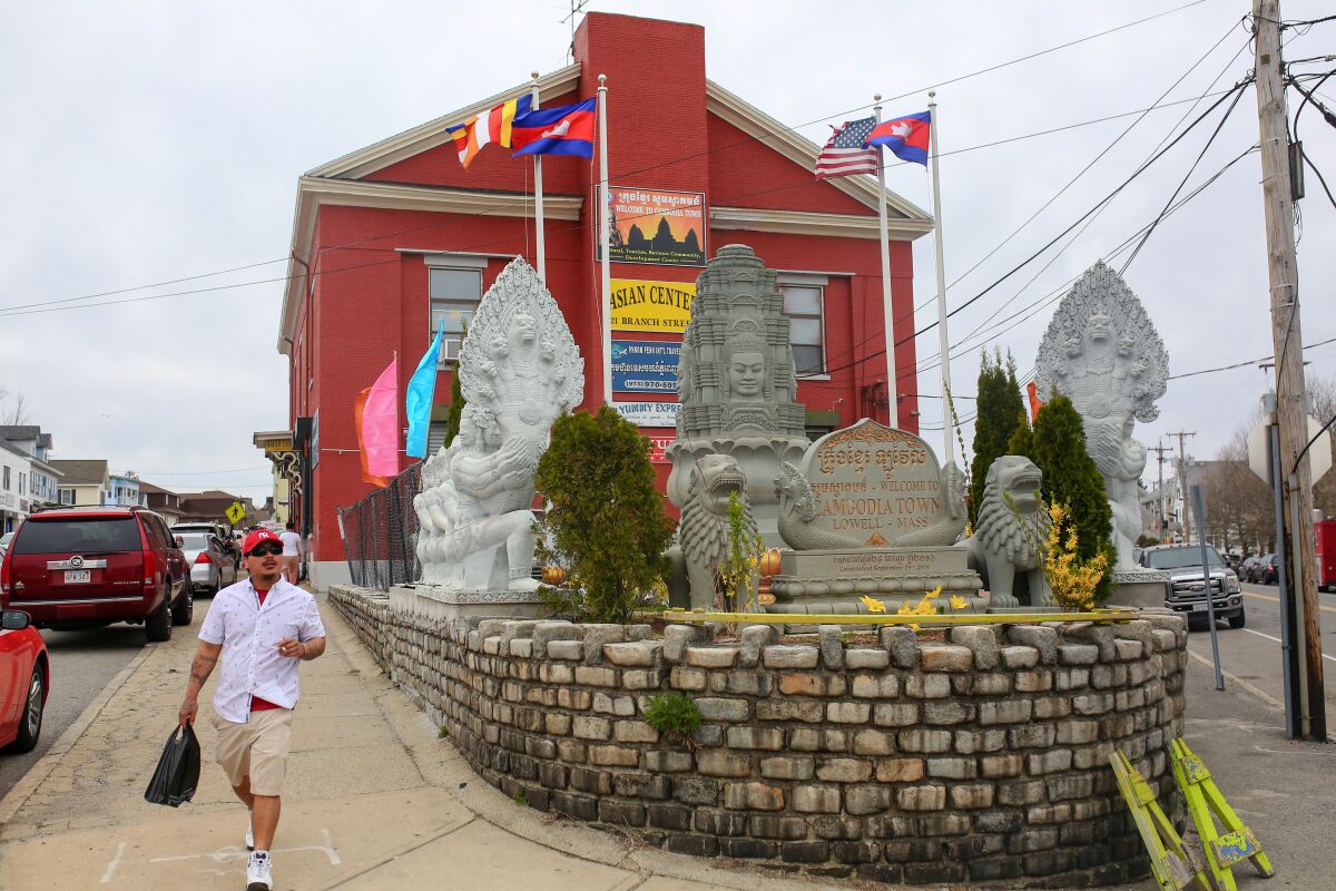 A man walks past the statues in front of the Asian Center in Lowell.
