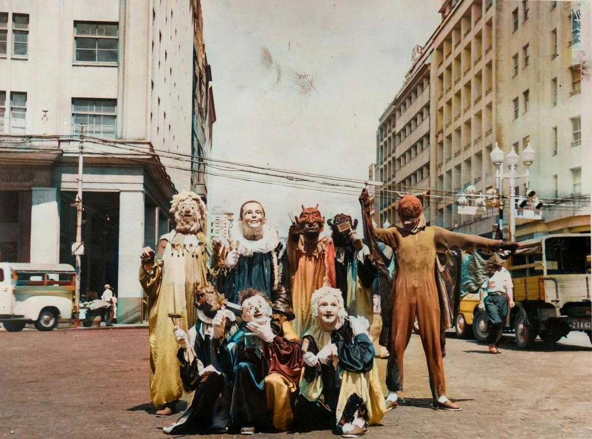 People dressed in costume stand on a street corner.