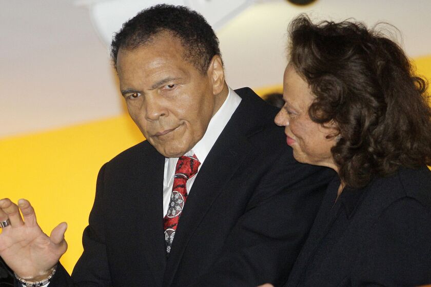 Muhammad Ali stands with his wife, Lonnie, while waving to friends attending his 70th birthday celebration at the Muhammad Ali Center in Louisville, Ky., on Jan. 14, 2012.