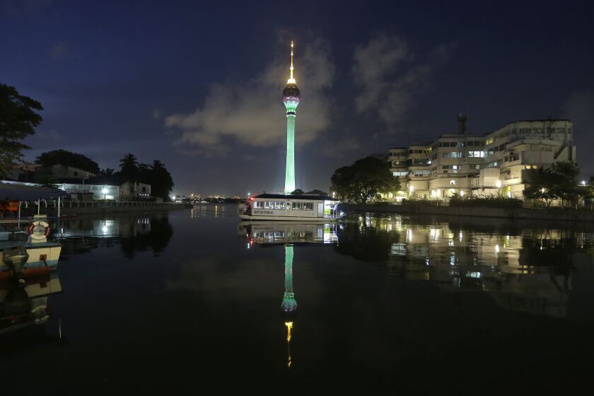 FILE - A ferry berths as a partially illuminated Colombo Lotus Tower, a multi complex digital transmission tower, is reflected in the water, a day after its opening in Colombo, Sri Lanka, Tuesday, Sept. 17, 2019. Sri Lanka marked its 75th independence anniversary on Saturday, Feb. 4, 2023, as a bankrupt nation, with many citizens angry, anxious and in no mood to celebrate. (AP Photo/Eranga Jayawardena, File)