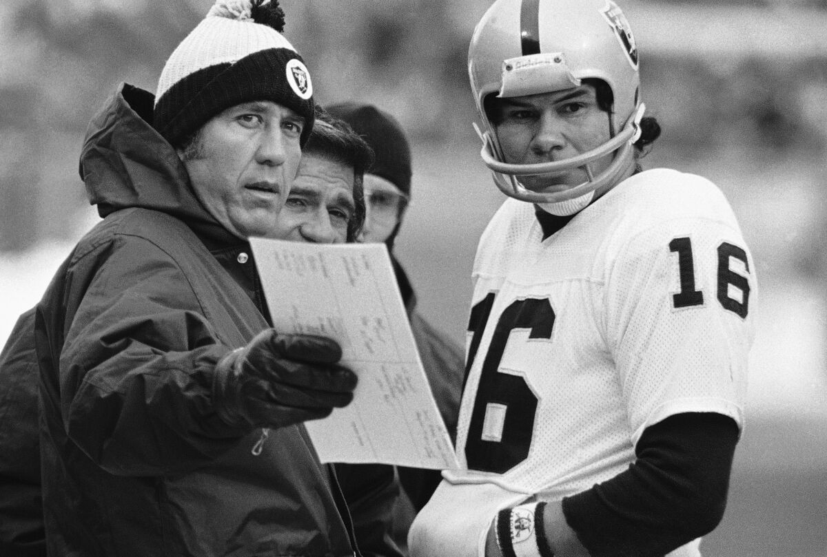 Oakland Raiders head coach Tom Flores talks over a play with quarterback Jim Plunkett.