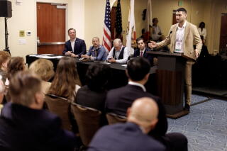 A man stands at a lectern in front of an audience in a room.