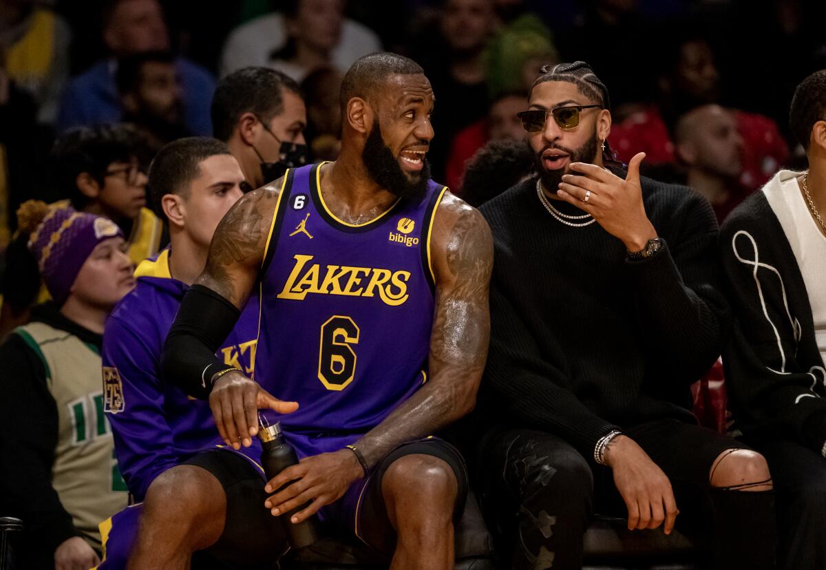 Injured Lakers forward Anthony Davis, right, chats with LeBron James on the bench during the first half Friday.