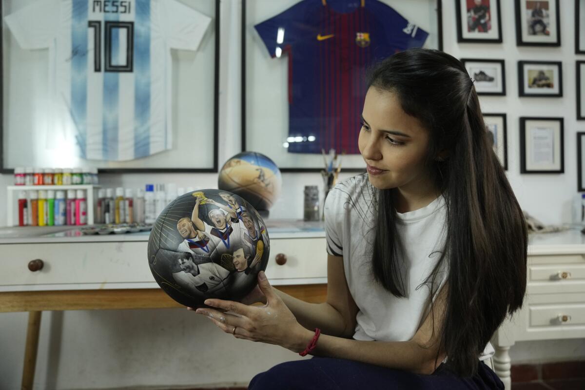 La artista plástica paraguaya Lili Cantero sostiene un balón de fútbol pintado a mano e ilustrado 