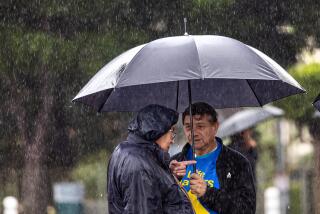 LOS ANGELES, CA - JANUARY 20: Two men attending the10th annual OneLife LA stand in heavy downpour at La Placita Olvera on Saturday, Jan. 20, 2024 in Los Angeles, CA. (Irfan Khan / Los Angeles Times)