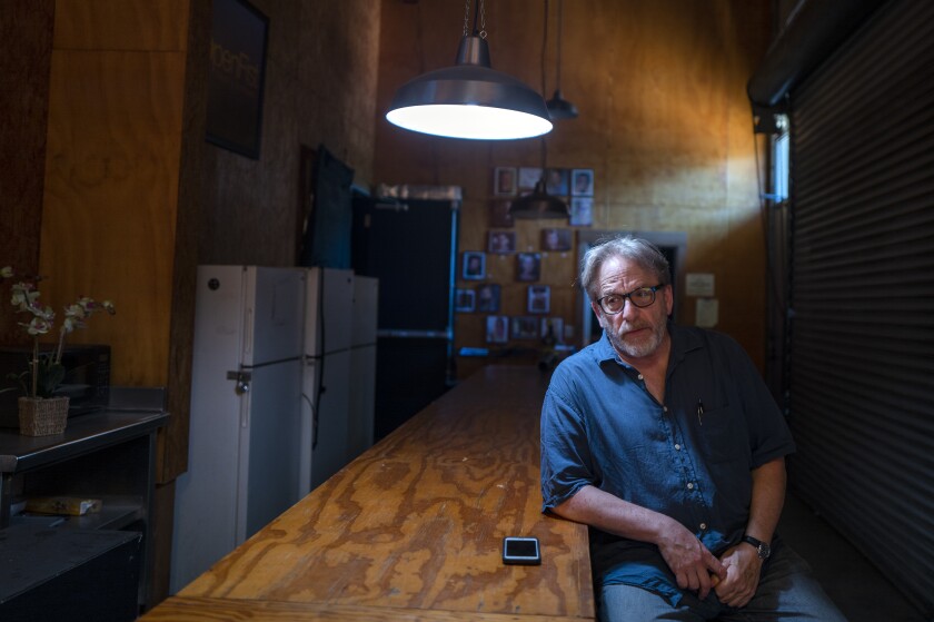 Chris Fields sits with an elbow on a wooden counter in a room where a ray of light pours in from a clerestory window
