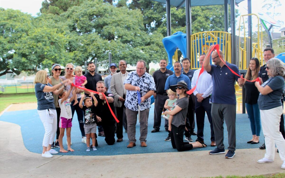 Costa Mesa Mayor John Stephens, center, cuts the ribbon Monday on a new playground at Jordan Park on the city's east side.