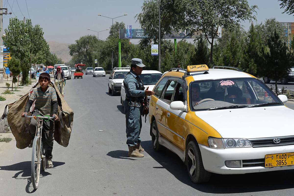 An Afghan policeman stops a car at a checkpoint where a foreigner was stabbed in Kabul on Aug. 20.