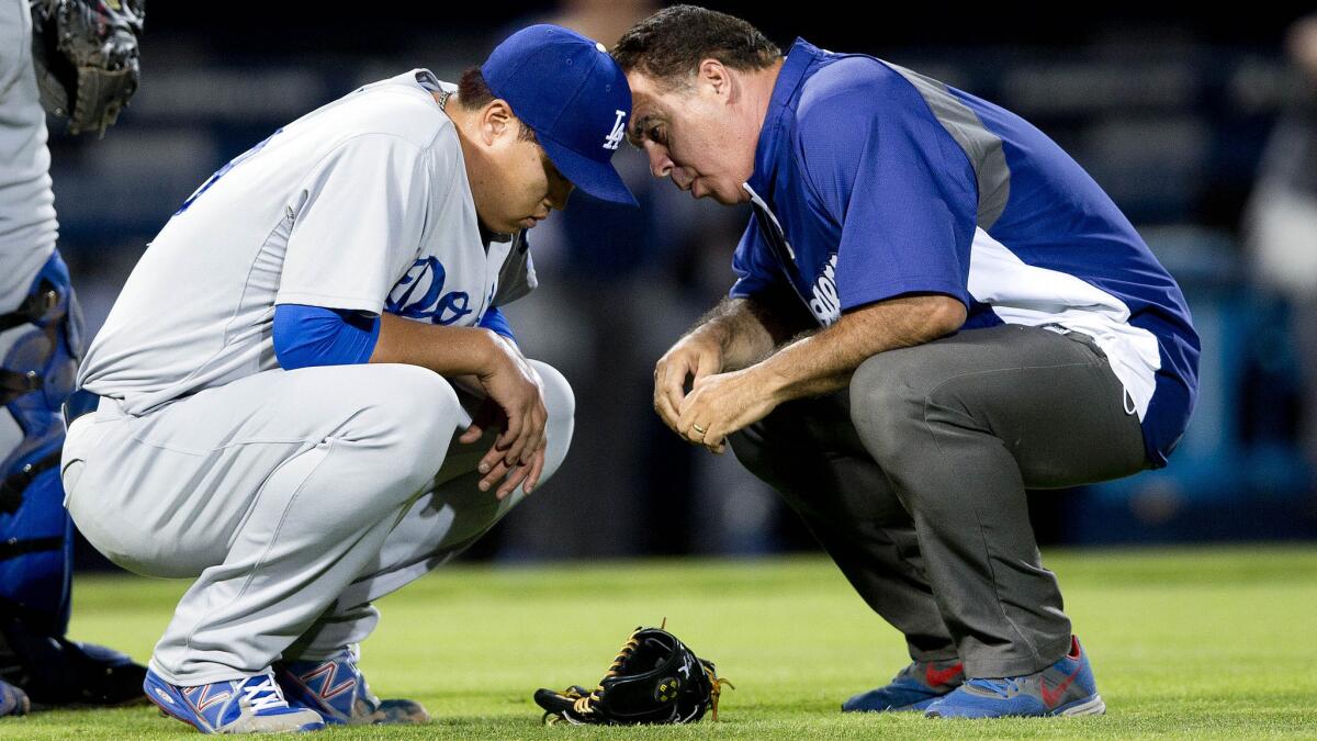 Dodgers starter Hyun-Jin Ryu speaks with a team trainer during the sixth inning of a 3-2 loss to the Atlanta Braves on Wednesday. Ryu suffered a right gluteus muscle strain and left the game.