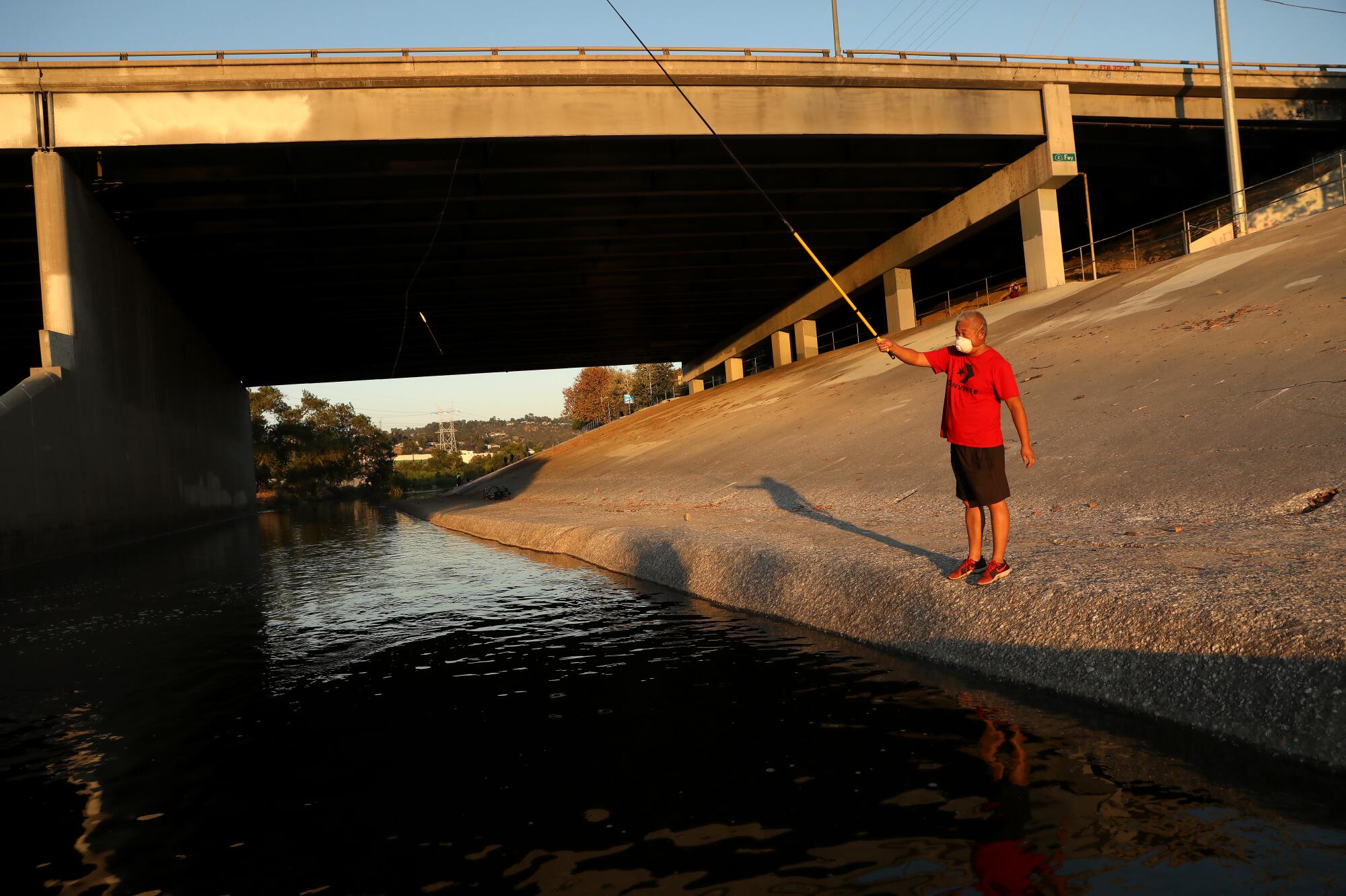 A man fishes the Los Angeles River in July