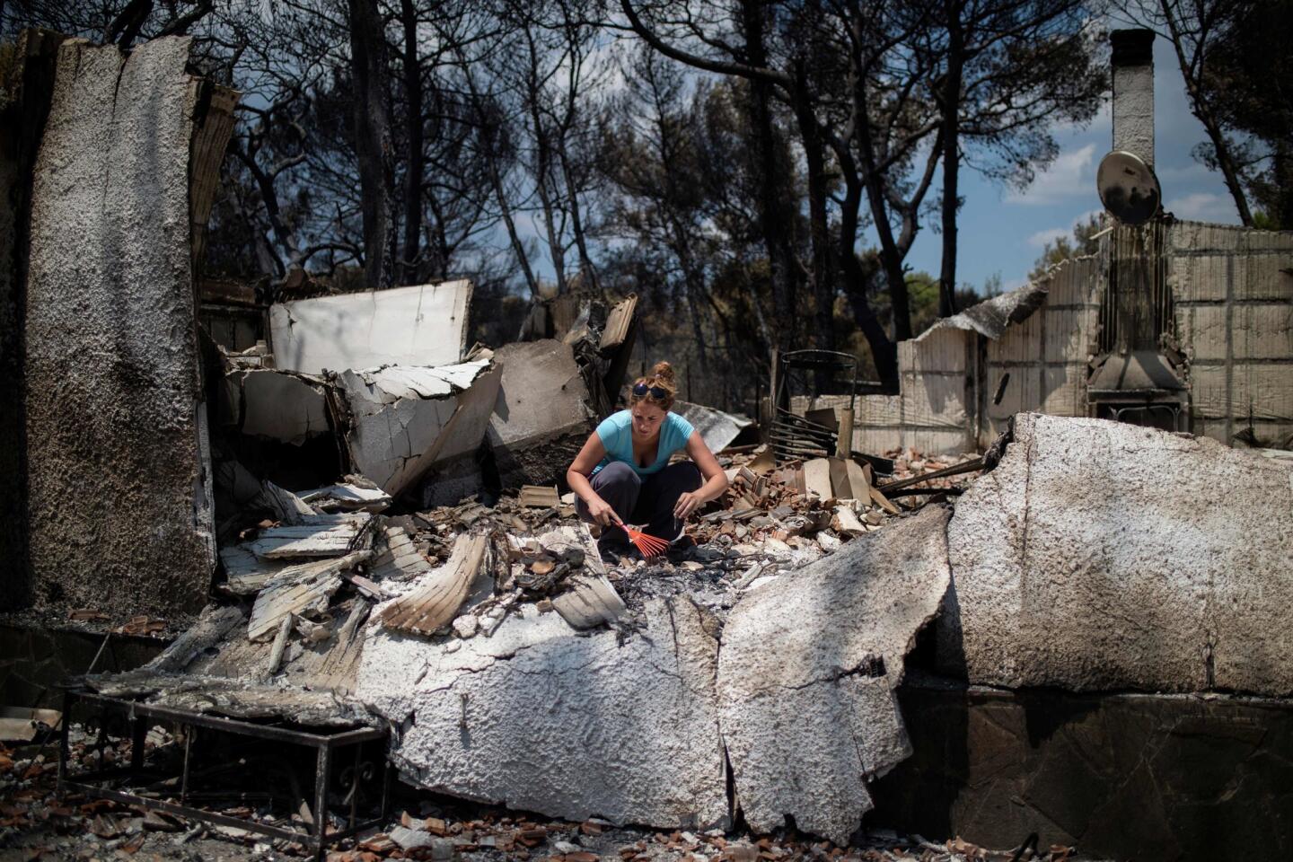 Una mujer busca rescatar algo de su hogar quemado, cerca de Atenas. Más de 2,000 viviendas fueron dañadas en un fatal incendio forestal