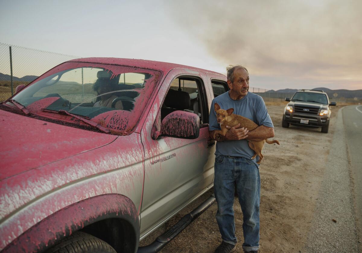 Rick Fitzpatrick holds a dog after evacuating from the Fairview Fire Monday, Sept. 5, 2022, near Hemet, Calif. (AP Photo/Ethan Swope)