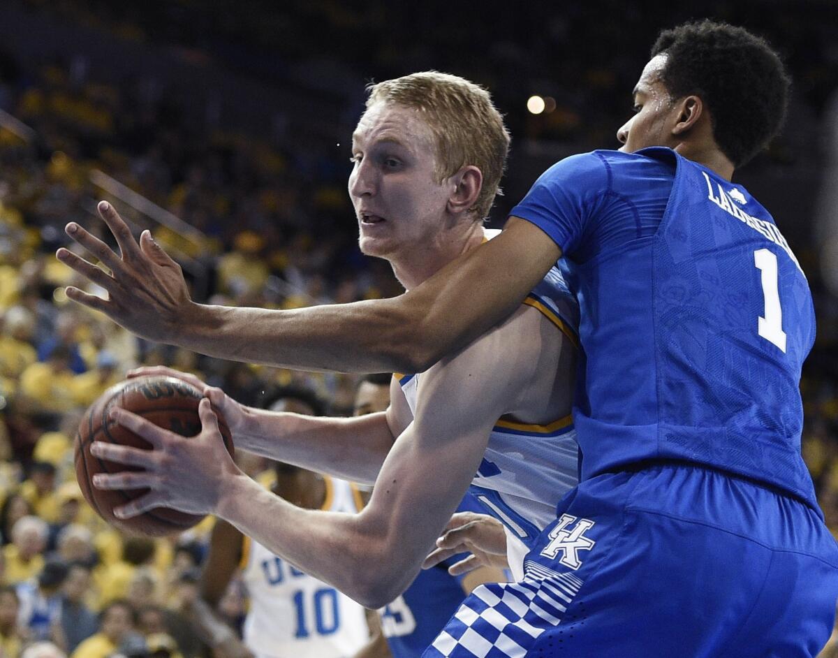 UCLA center Thomas Welsh, left, moves the ball as Kentucky forward Skal Labissiere defends.