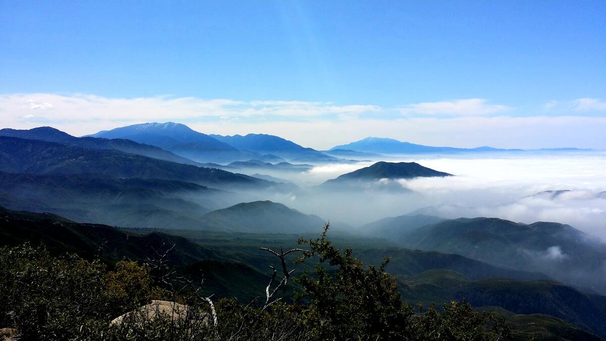 A wide view of a mountain range with clouds rolling in to the right.