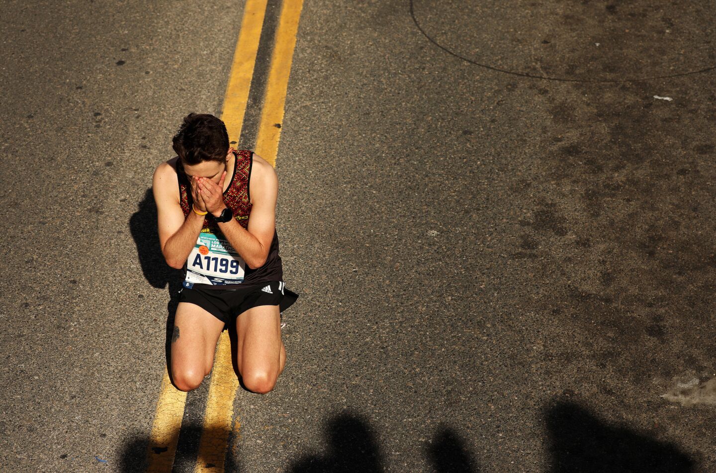 Race participant Armando Osorio drops to his knees after crossing the finish line in Santa Monica during the L.A. Marathon on Sunday.