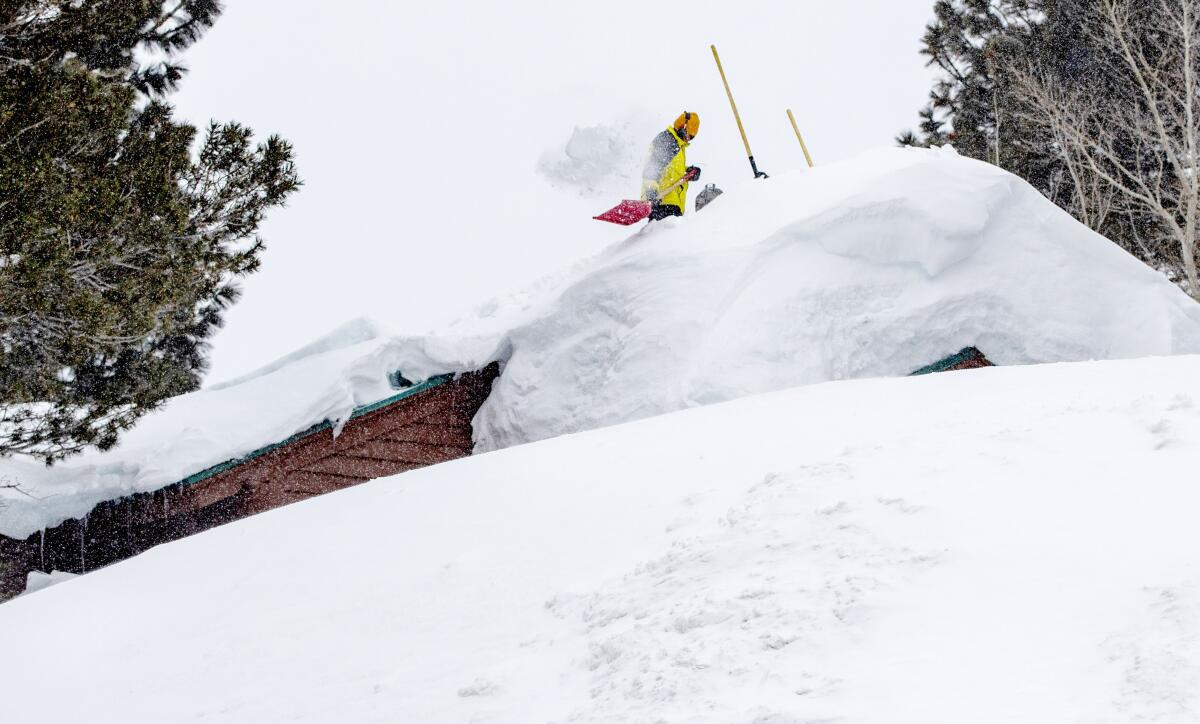 A resident clears snow off the roof of his house in Mammoth Lakes.