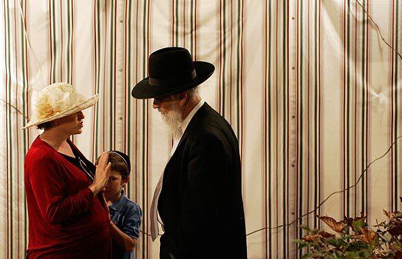 Rabbi Shalom Tendler talks to a guest and her son outside a sukkah during a Sukkot garden party at the home of Alan and Sharon Litman. Sukkot is a seven-day-long Jewish holiday celebrating God's bounty and protection, and usually coincides with the end of the harvest.