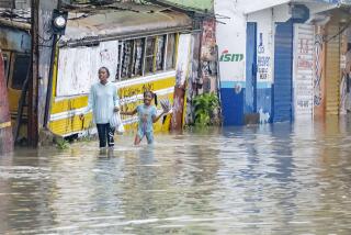 People walk through a street flooded by the rains of Tropical Storm Franklin in Santo Domingo, Dominican Republic, Tuesday, Aug. 22, 2023. (AP Photo/Ricardo Hernandez)