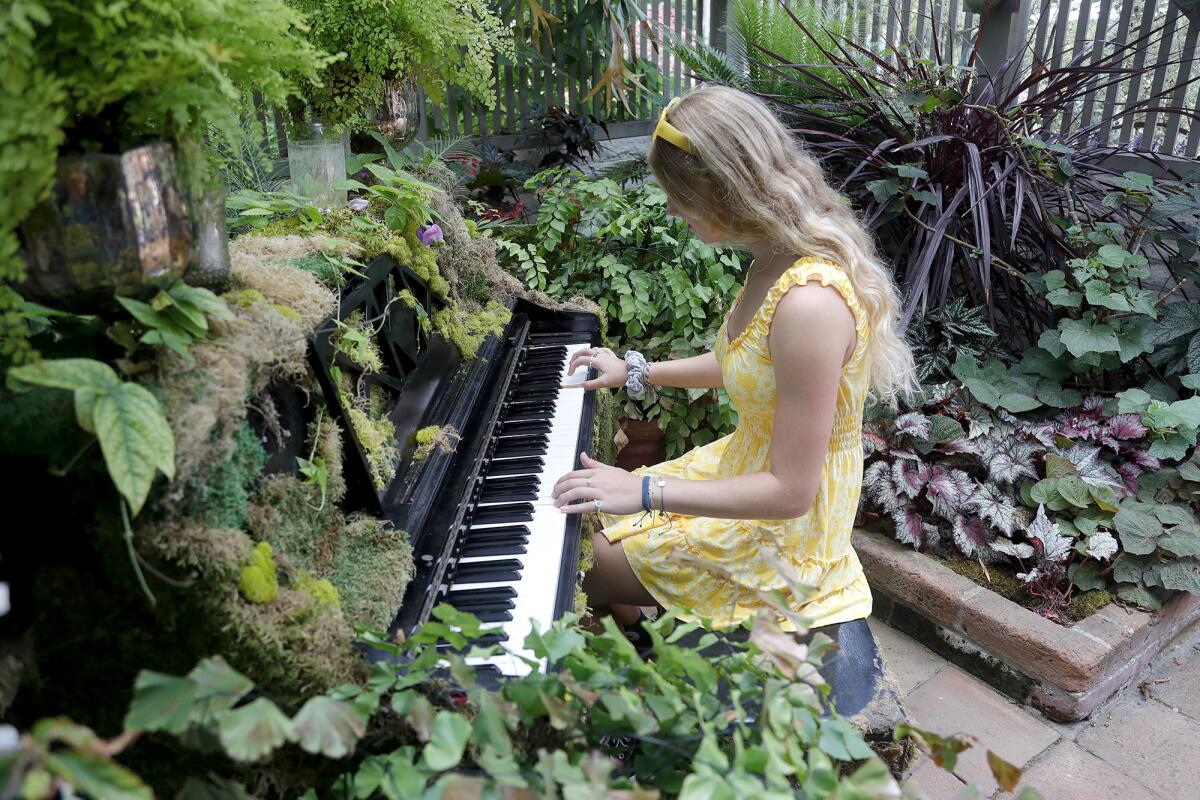 Visitor Hayley Esquino plays in the "music chamber" of the summertime greenHOUSE exhibit at Sherman Gardens Wednesday.