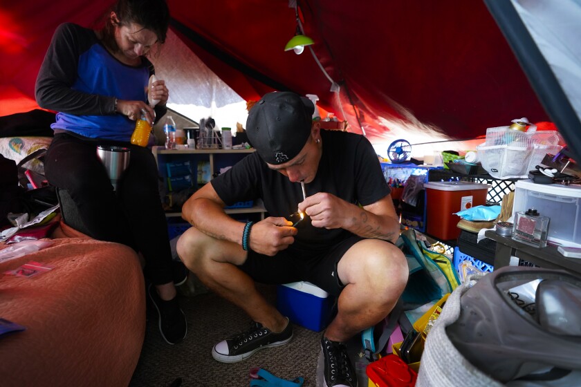 A homeless man smokes fentanyl inside his tent at a homeless encampment on May 12 in San Diego.