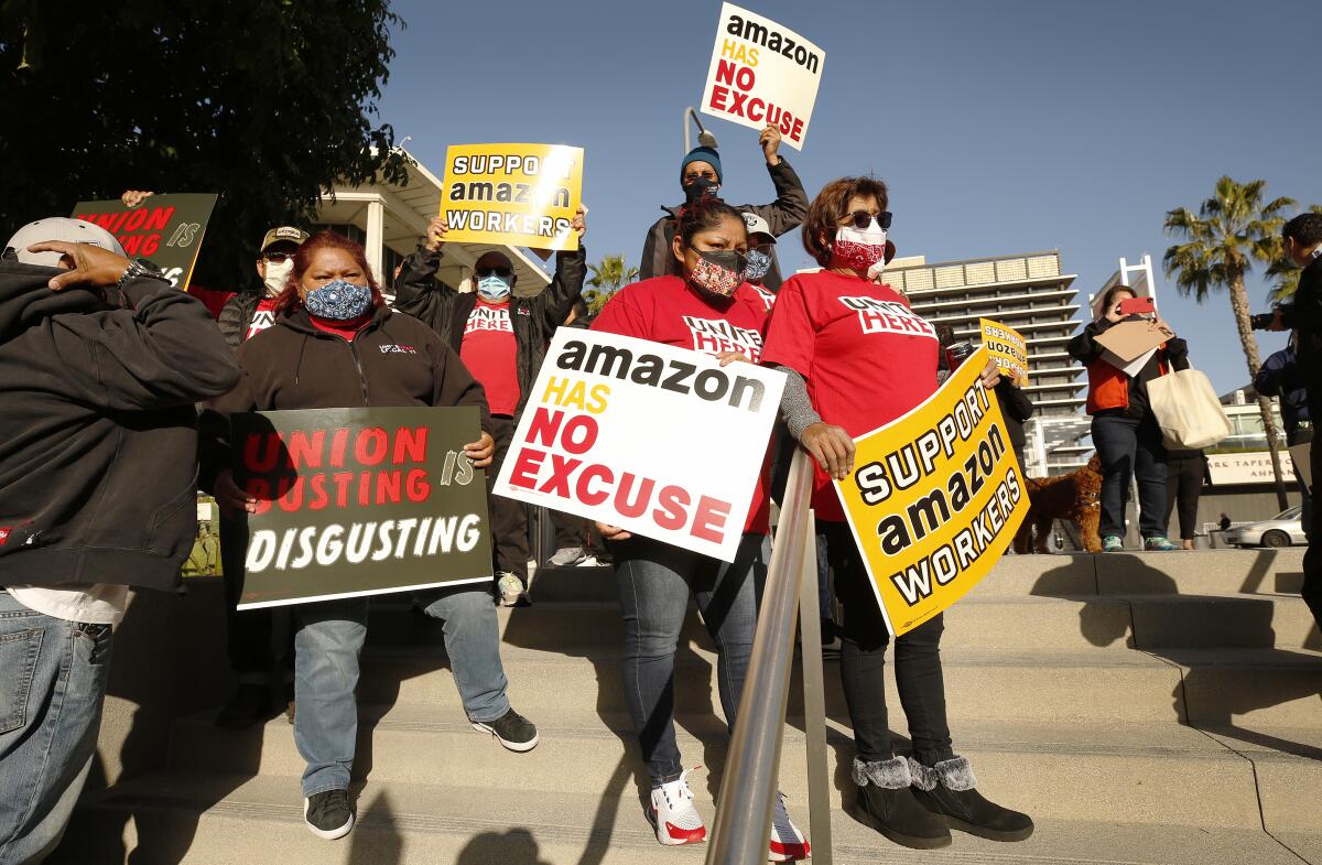 People hold signs in support of Amazon workers on steps outdoors
