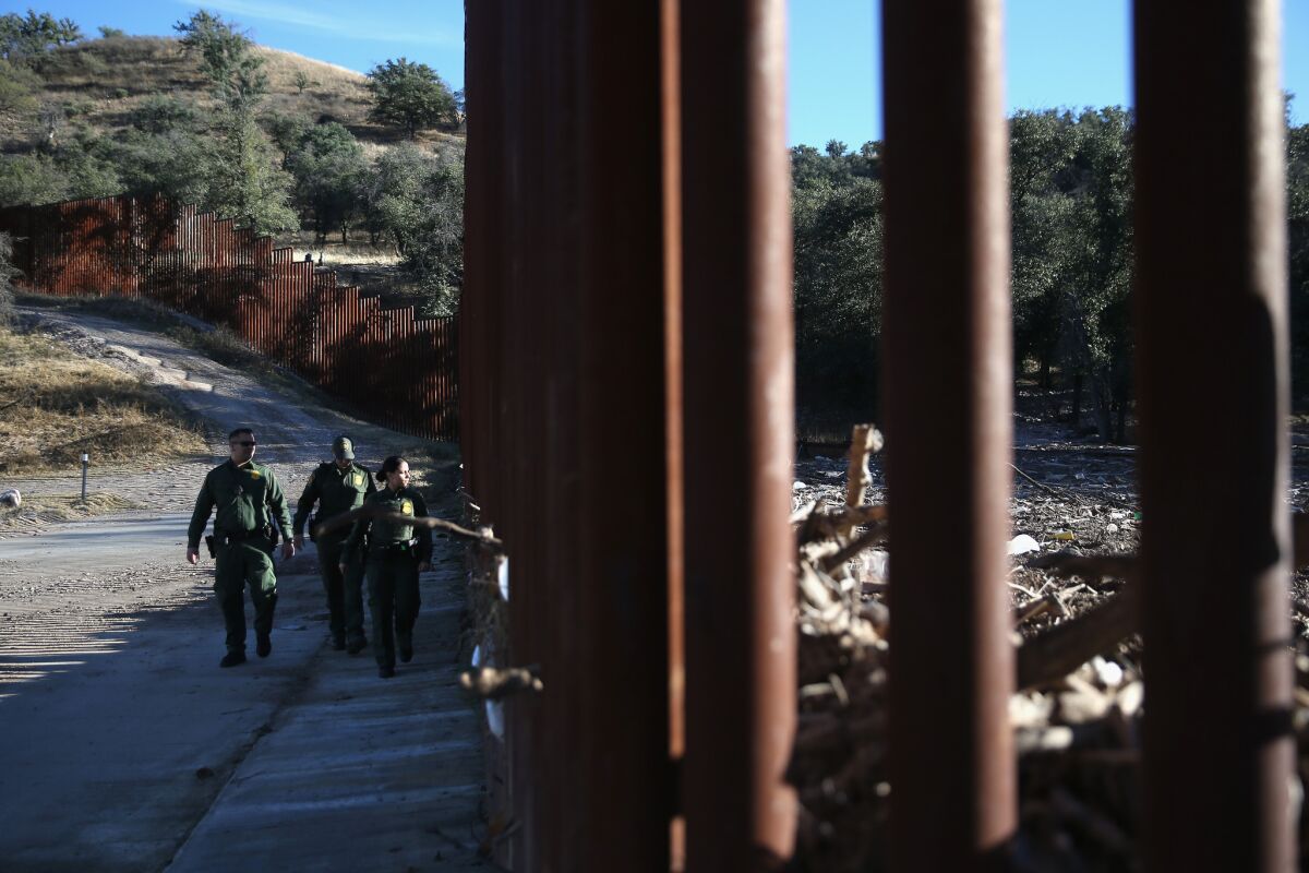U.S. Border Patrol agents walk along the U.S.-Mexico border fence on Dec. 9, 2014, near Nogales, Ariz.