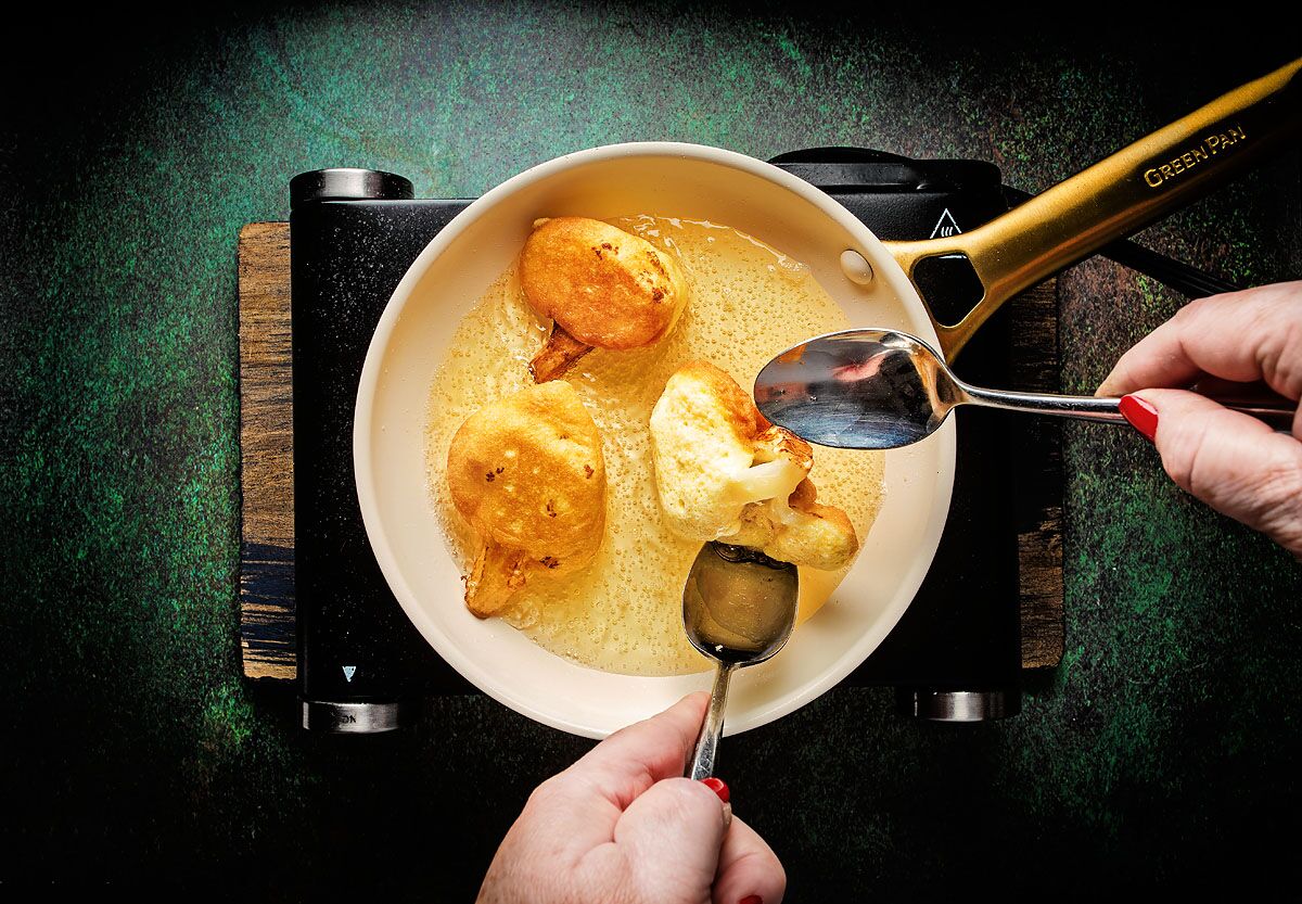 Use two spoons to carefully flip the egg-battered florets.