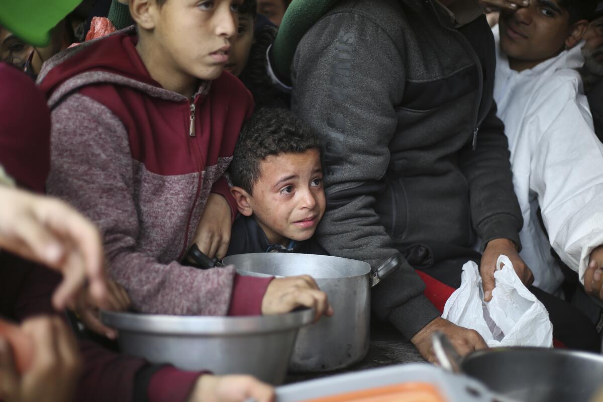 Los palestinos hacen fila para la distribución gratuita de alimentos durante la actual ofensiva aérea 