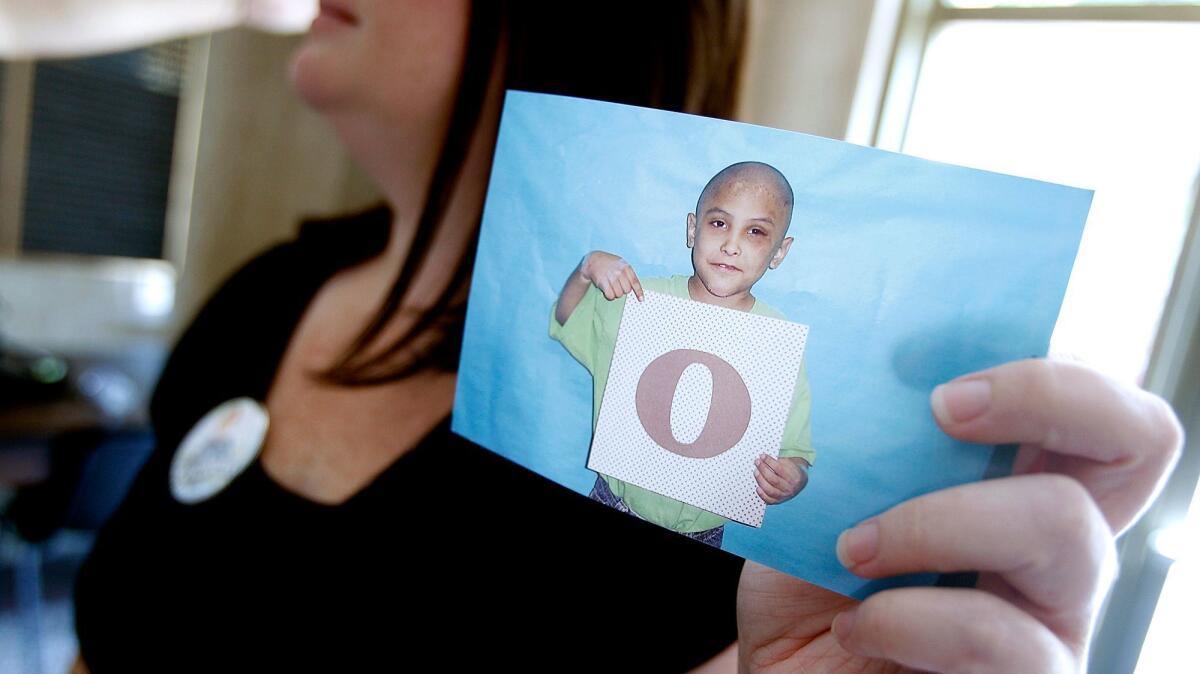 A concerned citizen holds a photo of Gabriel Fernandez, an 8-year-old boy who police say was tortured and killed by his mother and her boyfriend. Four L.A. County social workers are facing child abuse charges their roles in the Fernandez case.