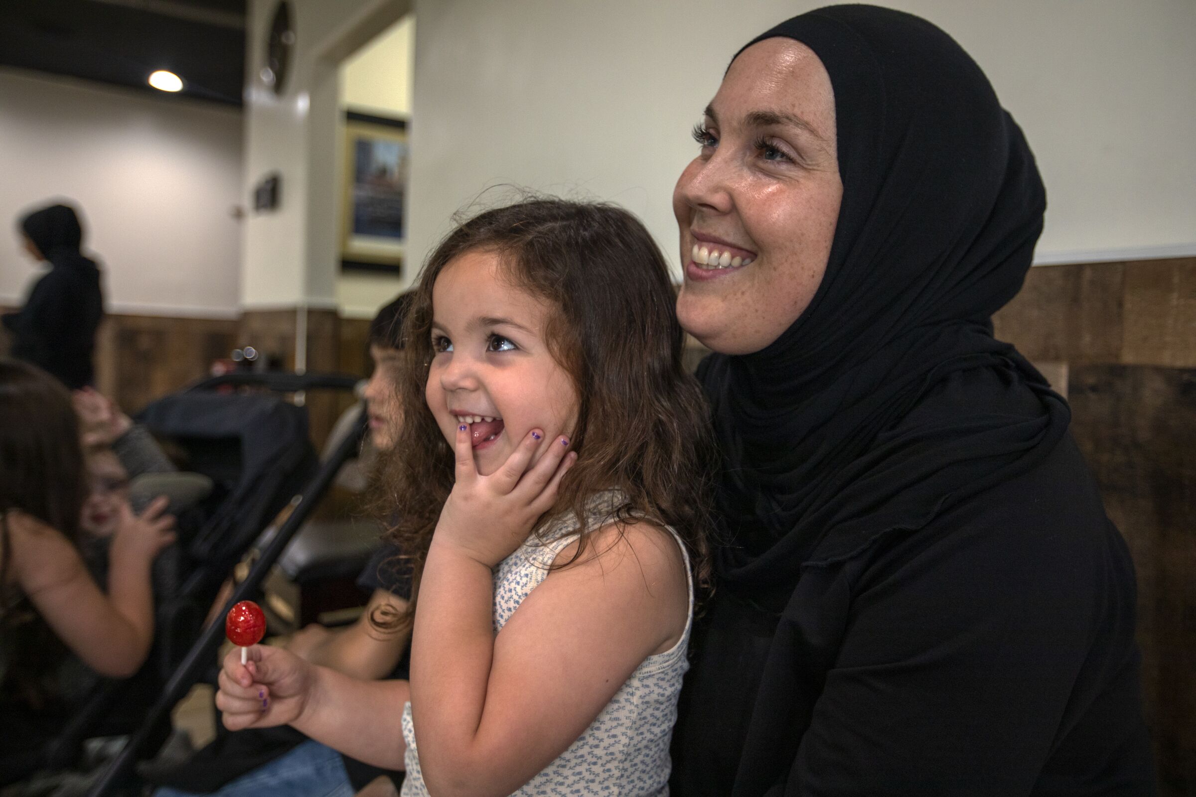 A hijab-wearing mother and 3-year-old daughter smiling.