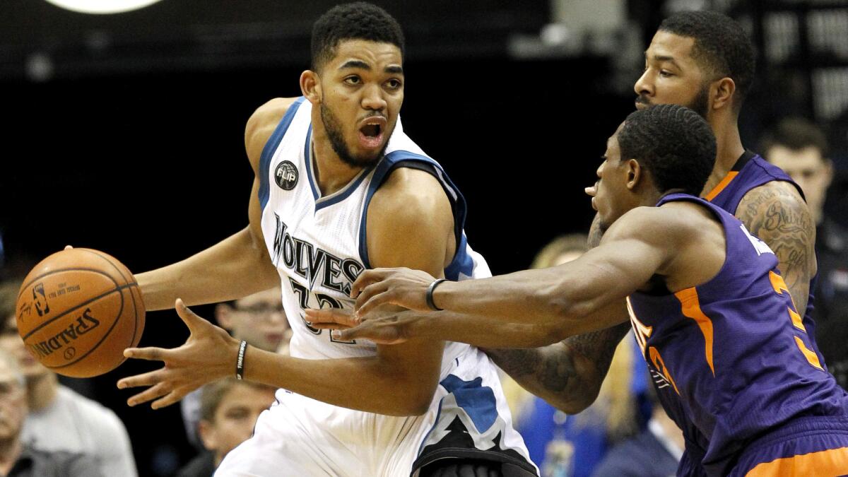 Timberwolves center Karl-Anthony Towns, looks to pass away from the double-team defense of Suns guard Brandon Knight and forward Markieff Morris on Sunday.