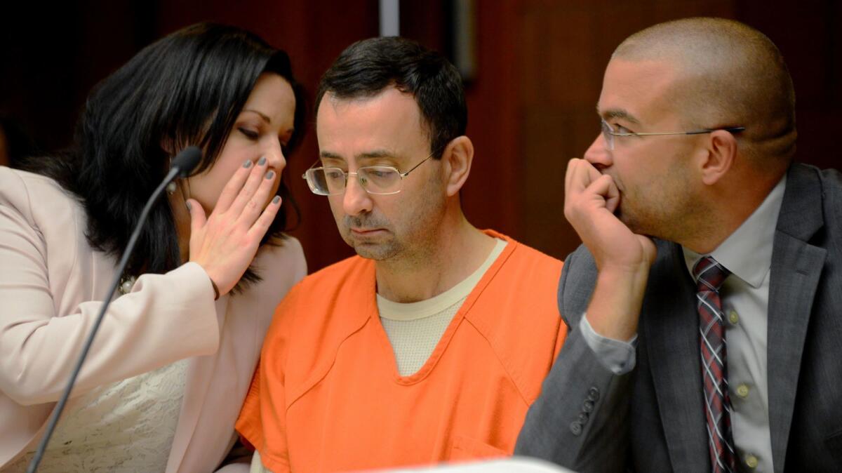 Dr. Larry Nassar, accused of sexually abusing U.S. gymnasts, sits between defense attorneys Shannon Smith and Matt Newberg during a preliminary hearing on May 26 in Mason, Mich.
