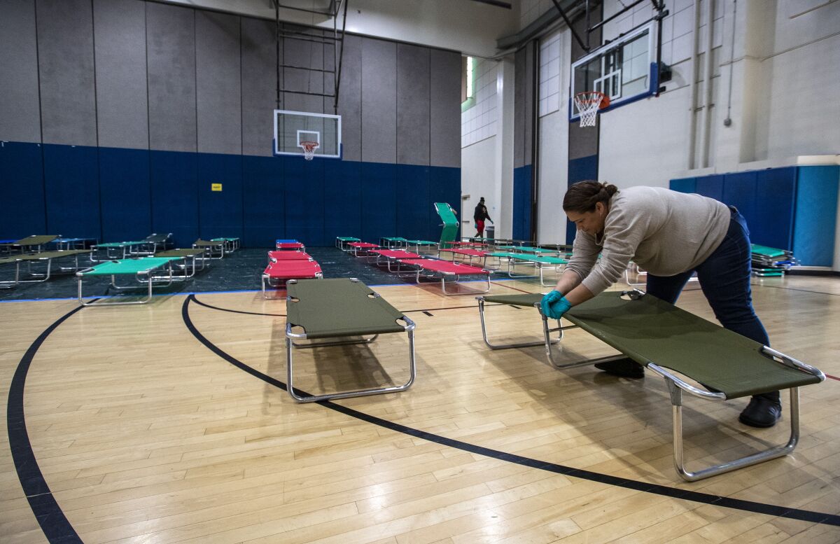 Salvation Army volunteer Christina Cuevas sets up cots for homeless people at Westwood Recreation Center in Los Angeles.