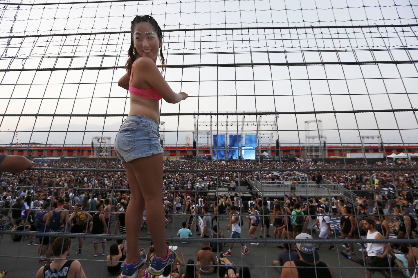 Kana Nan, 20, climbs the fence to get a look at Hard Summer, the Los Angeles dance music festival at the Auto Club Speedway in Fontana.