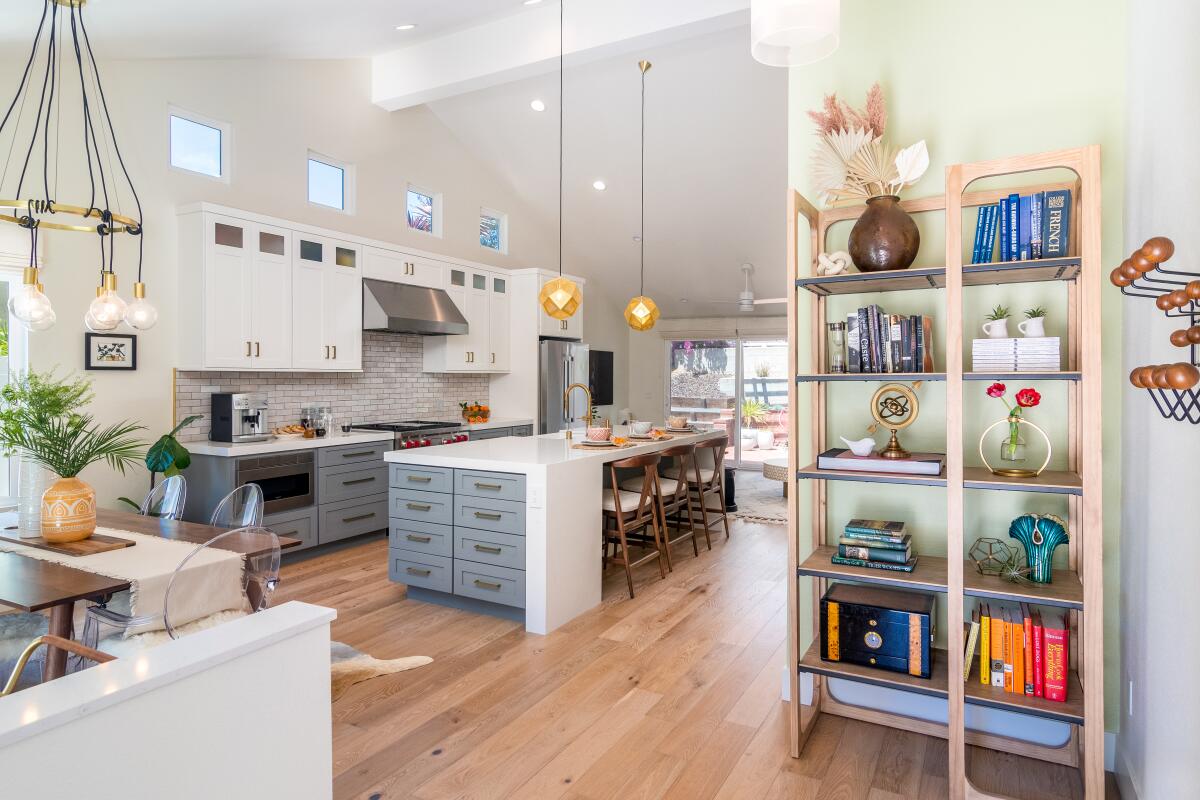 Greenery adds life to a modern kitchen, and a bookshelf displays curated items reflecting an owner's taste and interests.
