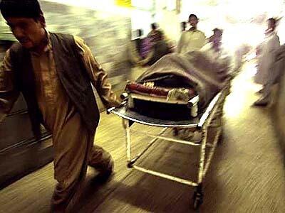 An Afghan bombing victim is whisked into the emergency room on a rusty gurney missing one of its wheels. The poor hospital often asks patients to buy their own medicine and supplies.