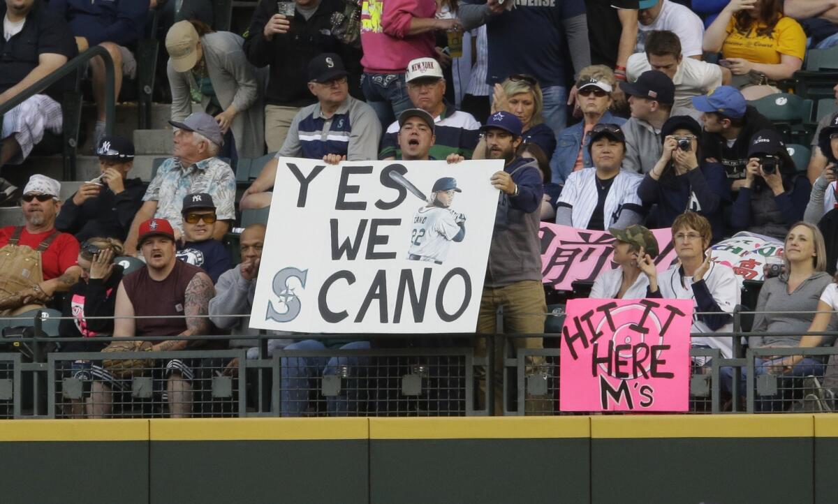 Fans hold signs supporting the Mariners' Robinson Cano during a game against the New York Yankees Wednesday in Seattle.