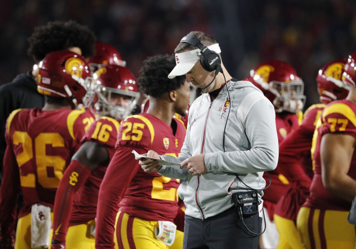 L'entraîneur-chef de l'USC, Lincoln Riley, vérifie sa liste de jeu lors d'un match contre la Californie.