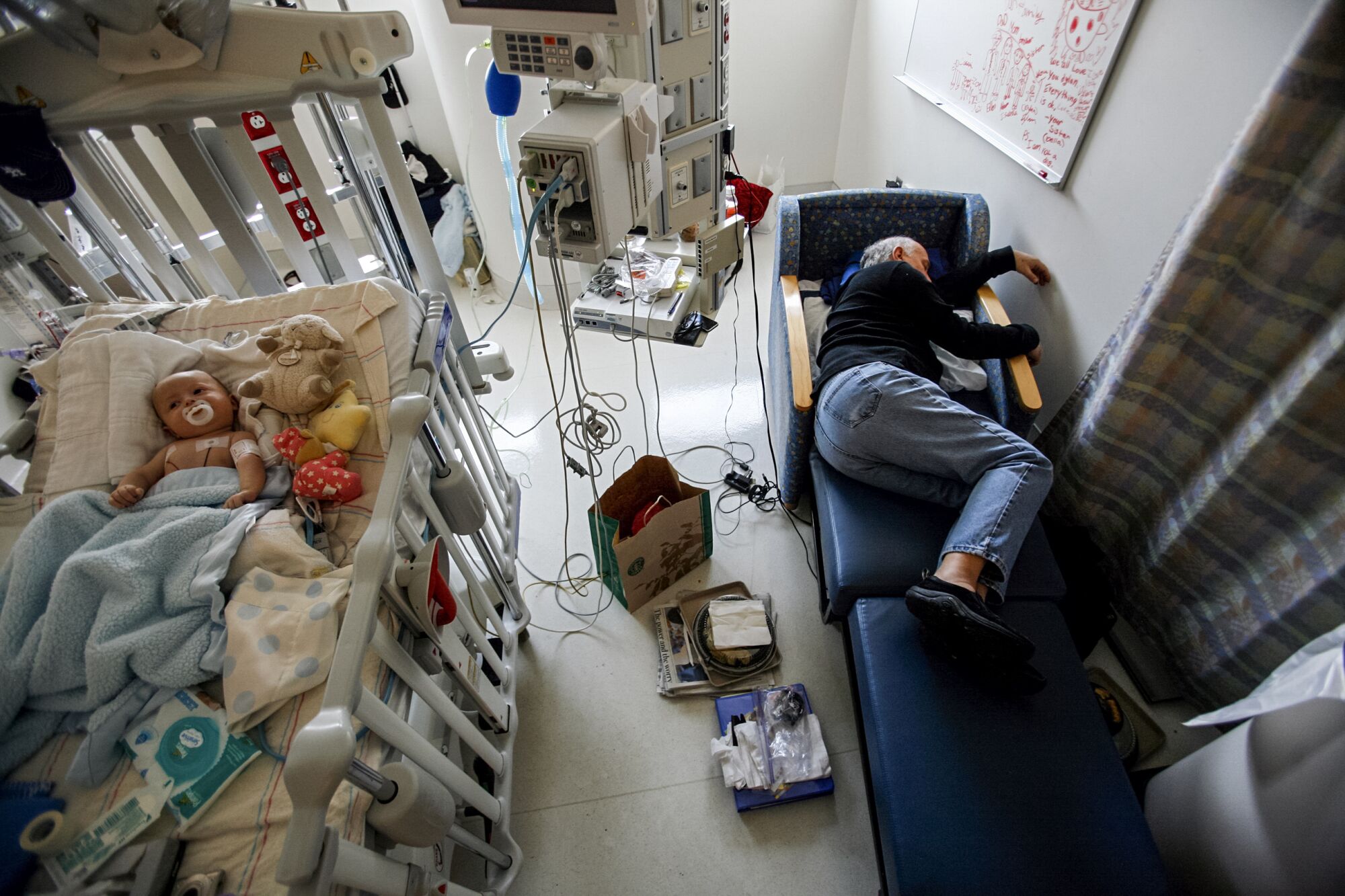  Jeff Catania, 60, falls asleep next to his two-month-old son Dylan in a hospital room