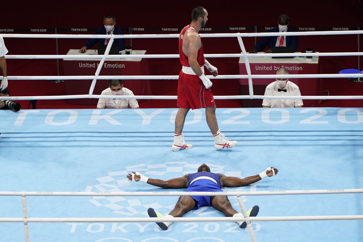Muslim Gadzhimagomedov, of the Russian Olympic Committee, top, walks past Cuba's Julio la Cruz as he lays on the mat in celebration after their men's heavyweight 91-kg boxing match at the 2020 Summer Olympics, Friday, Aug. 6, 2021, in Tokyo, Japan. (AP Photo/Frank Franklin II)