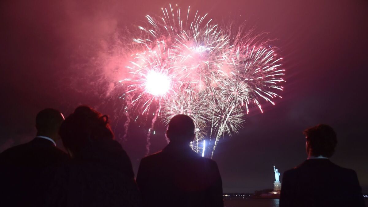 People watch fireworks from a ferry with a view of the Statue of Liberty in New York in May.