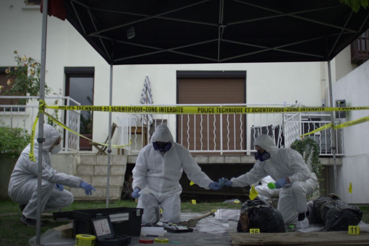 Three crime scene investigators in white hazmat suits gather evidence.