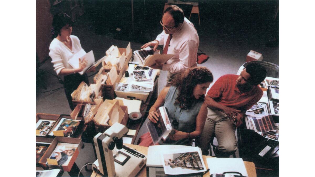 Los Angeles Times Orange County graphic director Lily Kuroda, left, and photographers Con Keyes, Marissa Roth and Michael Edwards, right, sort through hundreds of photos of the 1992 Los Angeles riots.