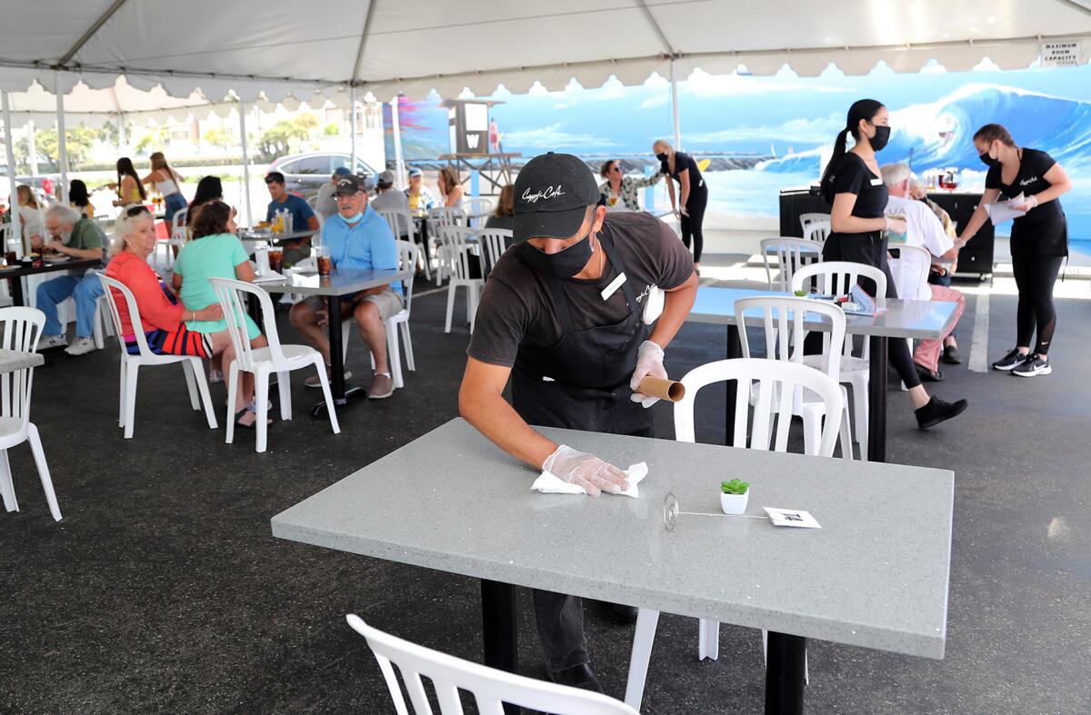 Arturo Guzman cleans a table in the outdoor dining area at Cappy's Cafe in Newport Beach.