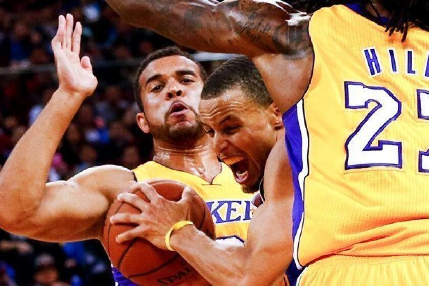 Lakers rookie Elias Harris, left, playing defense against Golden State's Stephen Curry in a preseason game.