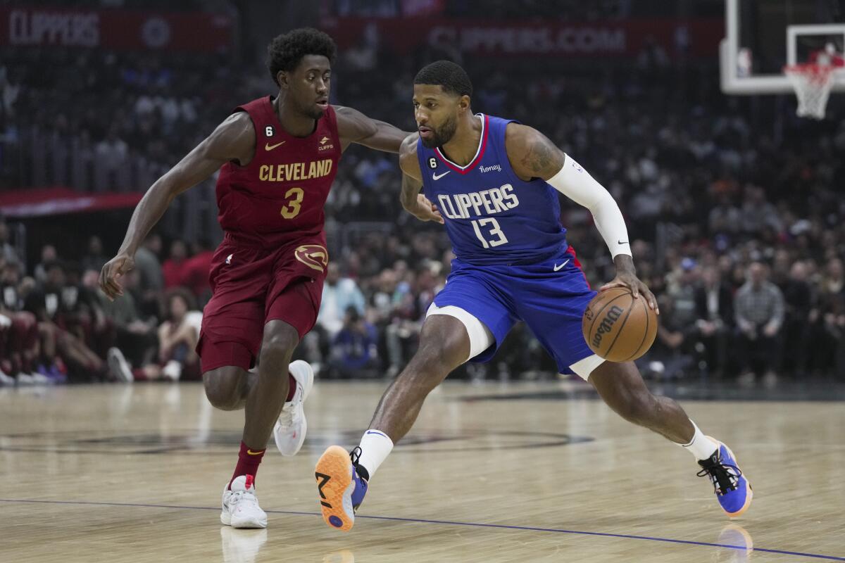 Clippers guard Paul George, right, controls the ball against Cleveland Cavaliers guard Caris LeVert.